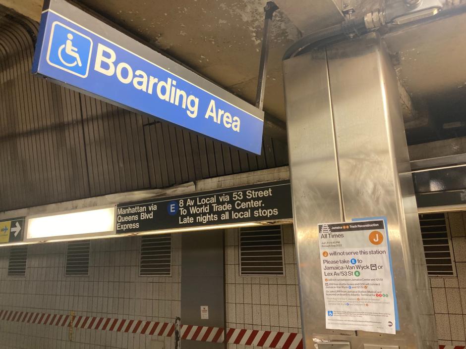 Signs on the platform at Jamaica Center indicate that the E train stops there, that this is the accessible boarding area, and that there is a service notice for the J line