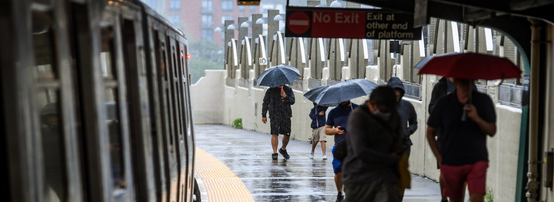 People walk on a subway platform during a rain storm. 
