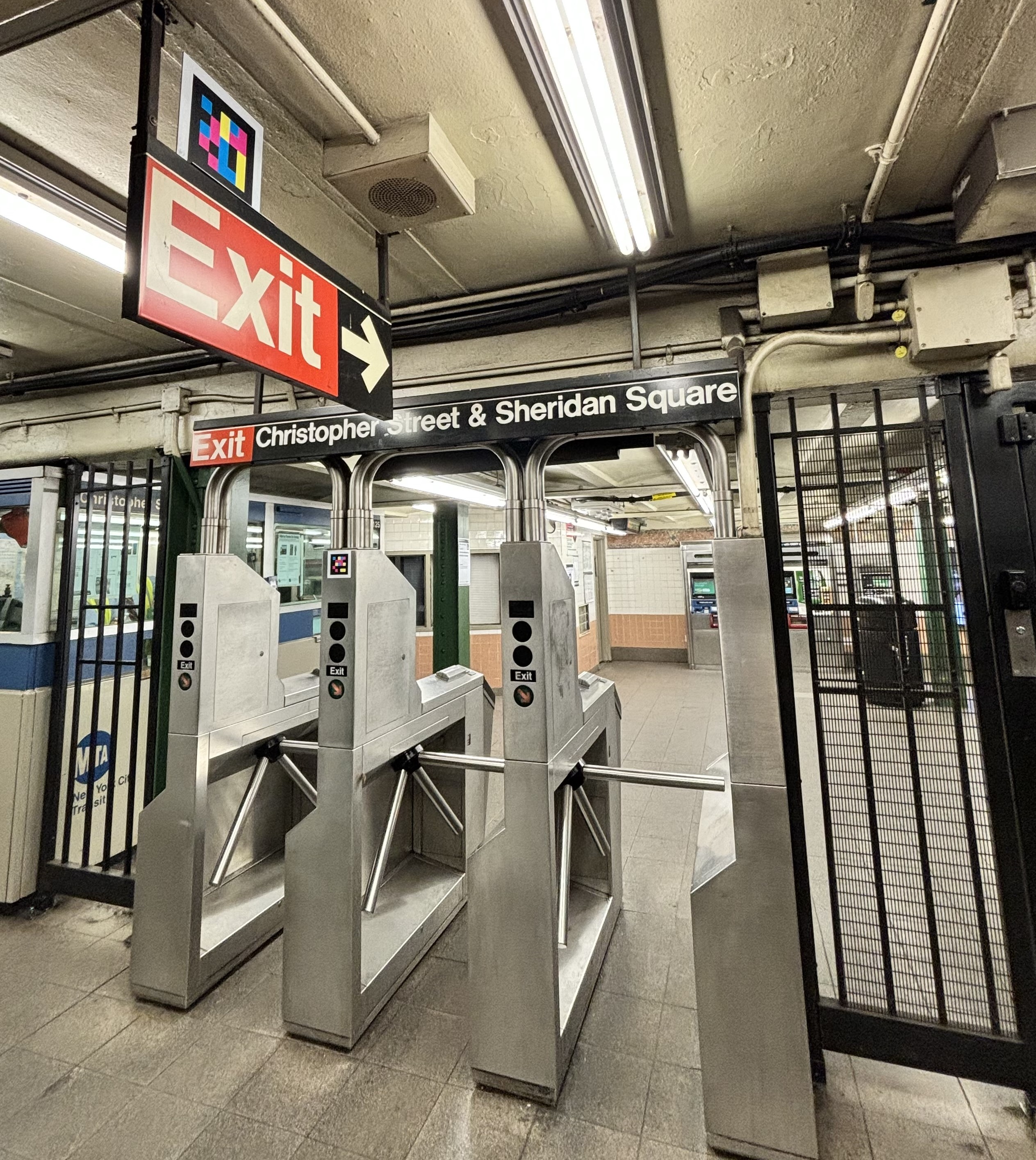 Exit turnstiles at Christopher St station. NaviLens codes are on the overhead exit sign and on the turnstiles.