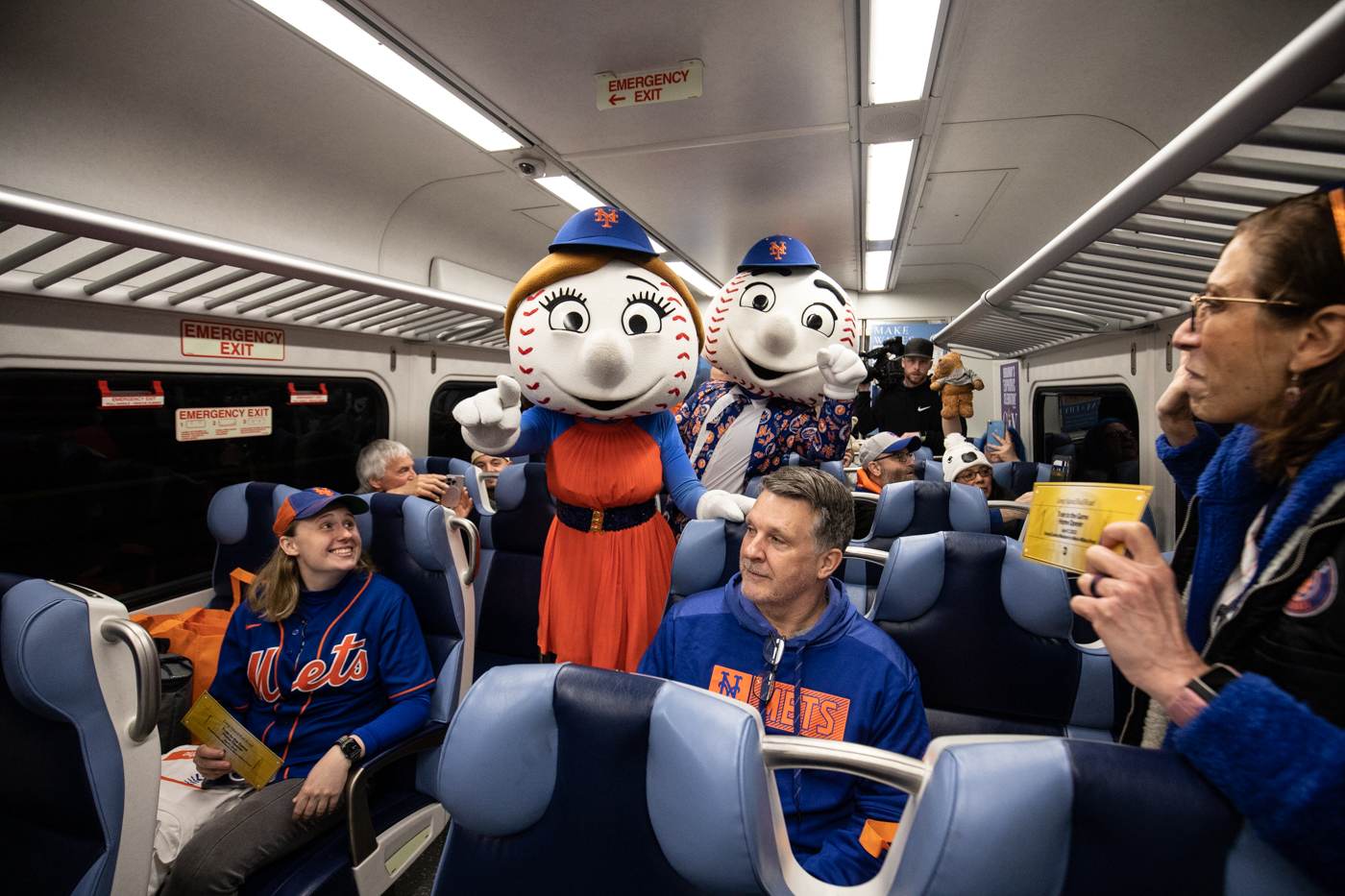 Mr. and Mrs. Met aboard a Long Island Rail Road train car filled with Mets fans