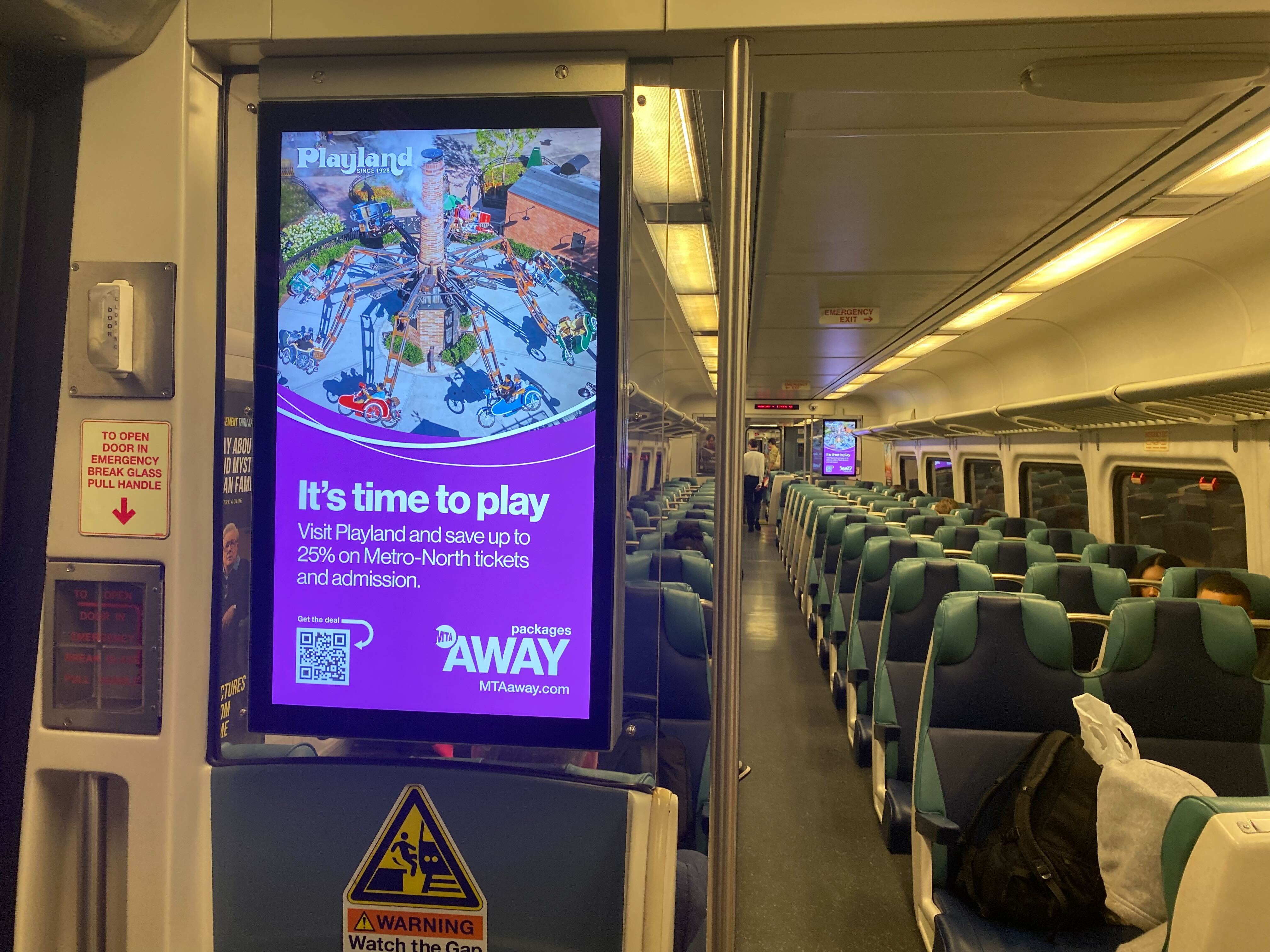 An ad for Rye Playland on a digital screen on a Metro-North train car
