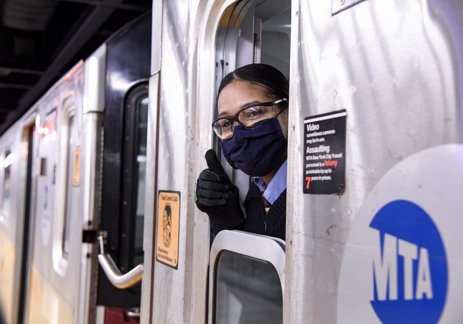 A train operator wearing a mask and giving a thumbs up. 
