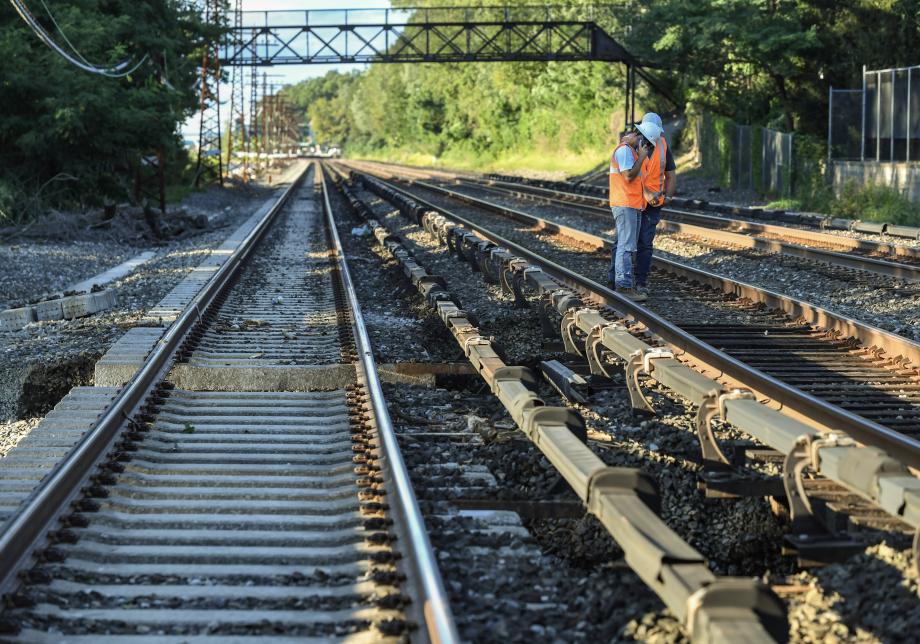 Railroad workers stand near a section of train track that was washed out in the aftermath of a severe storm.