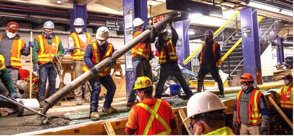 Workers pouring concrete on a subway platform